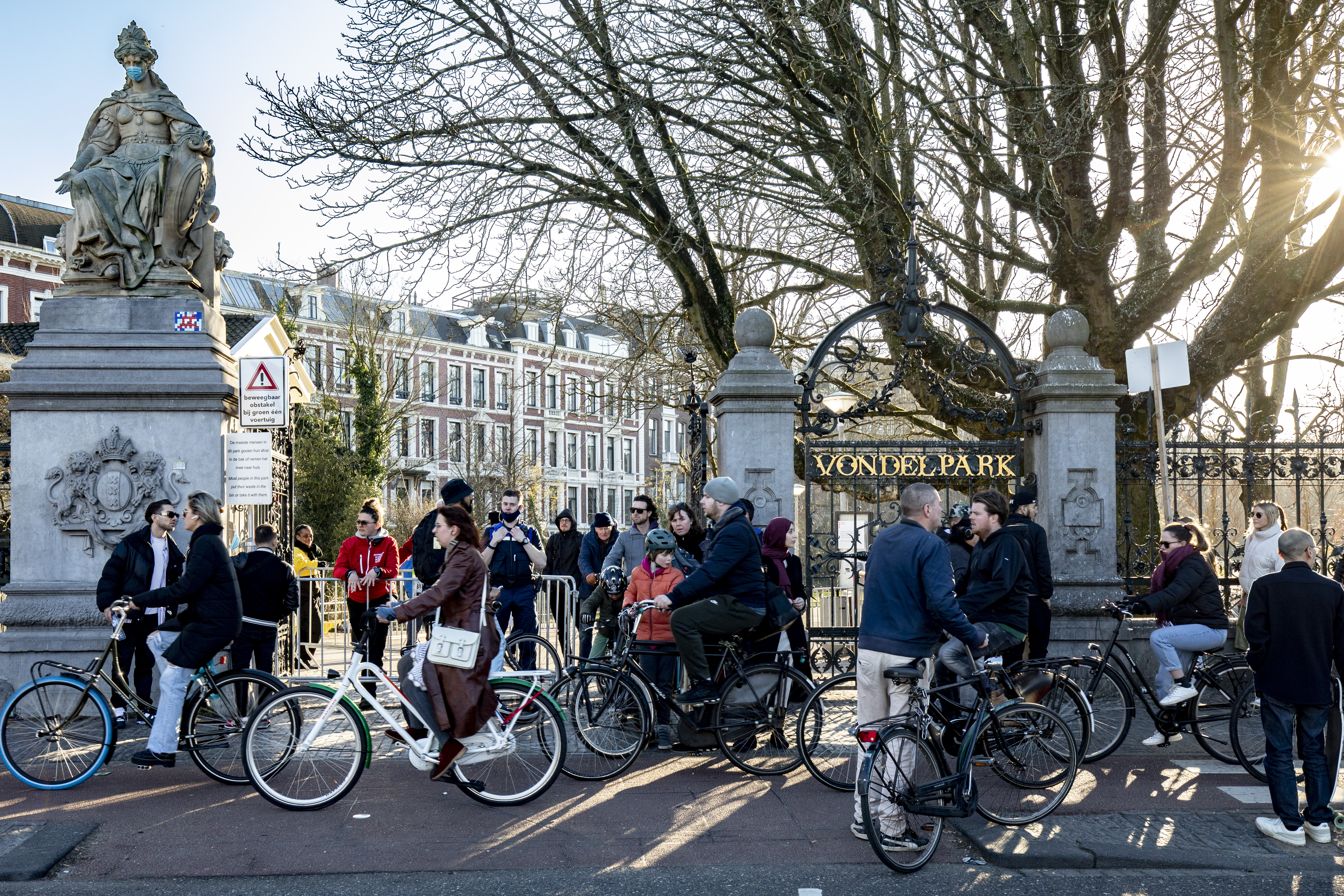 Cyclists and people mingle around one of the entrances to Vondelpark in Amsterdam, which closed to the public during the Covid-19 pandemic